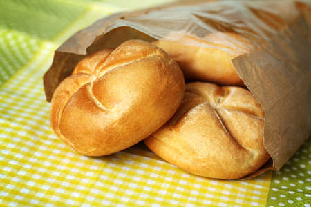 Three small buns made of white flour in paper bag
