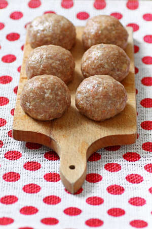 Six beef balls from minced meat laid on wooden cutting boardの写真素材