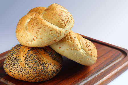 Three fresh white rolls on chopping board