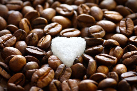 Close up of sugar heart in the middle of roasted coffee backgroundの写真素材