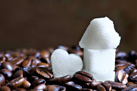 Close up of sugar hearts surrounded by roasted coffee beansの写真素材