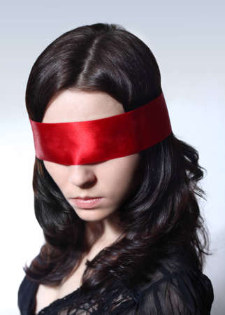 Portrait of a young Caucasian female with brown hair and red blindfolder over her eyesの写真素材