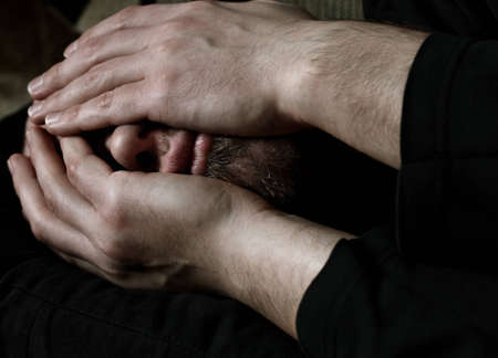 Close up of a Caucasian man covering face with hands from desperationの写真素材