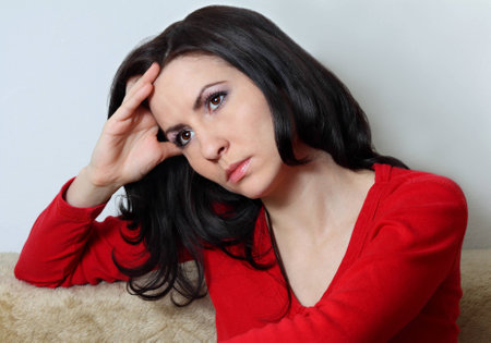 Young good looking brunette with long hair sitting supporting her head with handの写真素材