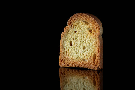 Close up of golden slice of toast on black background with reflection