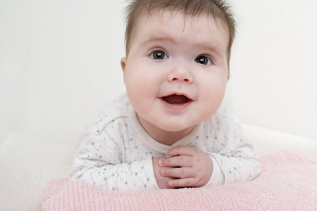 Close up of baby girl laying on her tummy happily smilling