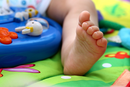 Close up of babies foot surrounded by toysの写真素材