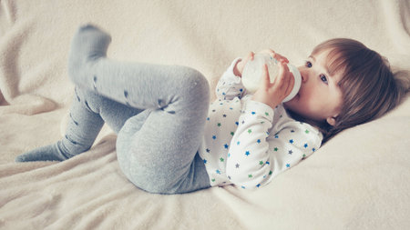 Enjoing her toddler drinking milk from bottleの写真素材