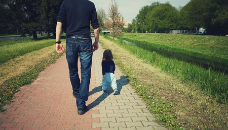 Child is walking with daddy on a sunny dayの写真素材