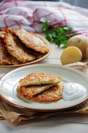 Plate of crispy hash browns prepared at home and served with sour creamの写真素材