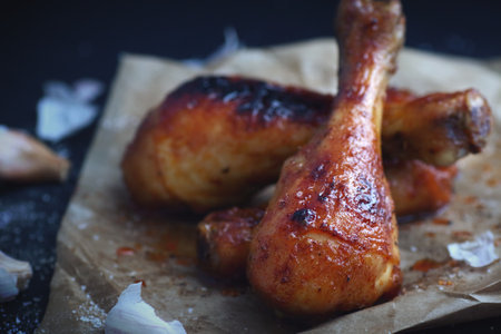 Homemade roasted chicken drumsticks with garlic on black background close upの写真素材