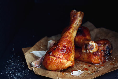 Homemade roasted chicken drumsticks with garlic on black background close upの写真素材
