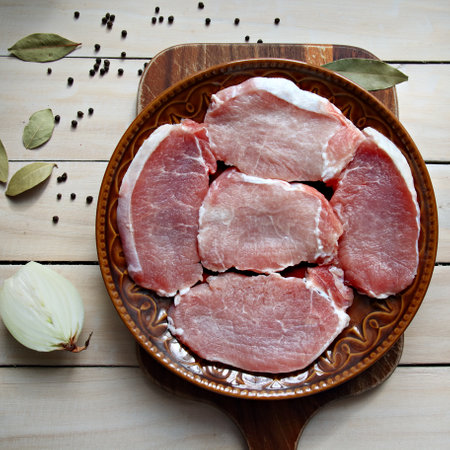 Pork raw steaks on a brown plate over wooden background top viewの写真素材