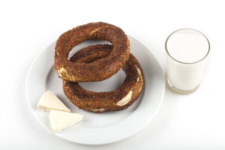 two simit that is circular bread on white dish with cheese and ayran