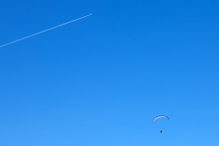 powered paragliding with a flying plane on background blue sky