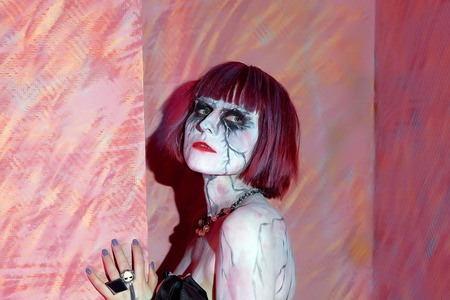 vampire girl with bare shoulders posing on a red background