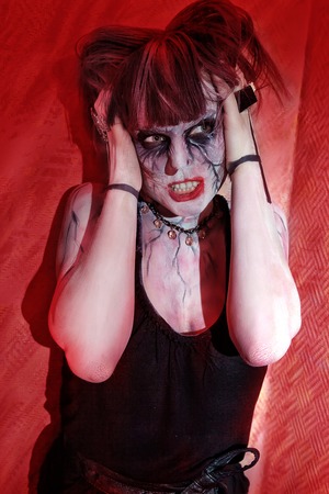 girl with makeup zombie horror shows against backdrop of red wall