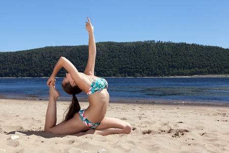 girl in bathing suit sitting on splits summer sunny beachの写真素材