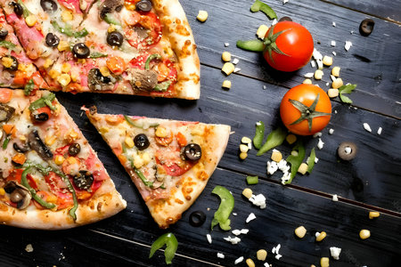 A mouthwatering top view of a pizza placed on a wooden table, with two juicy tomatoes resting beside...