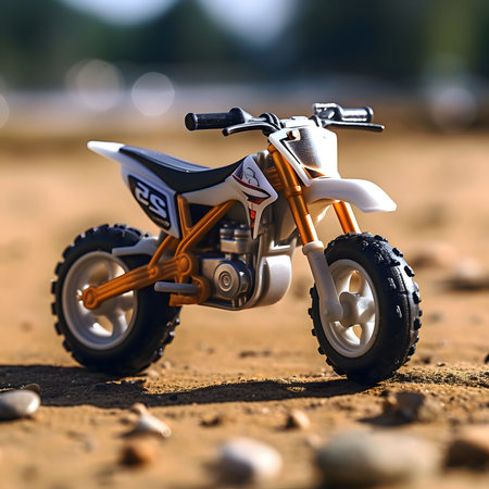A toy motocross bike, captured in a close-up shot, showing its intricate details. The dirt bike is positioned on a sandy surface, with its wheels and suspension visible.の写真素材