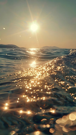 A close-up shot of the ocean with golden sunlight reflecting off the water. The sun is shining brightly in the sky, creating a beautiful and peaceful atmosphere.の写真素材