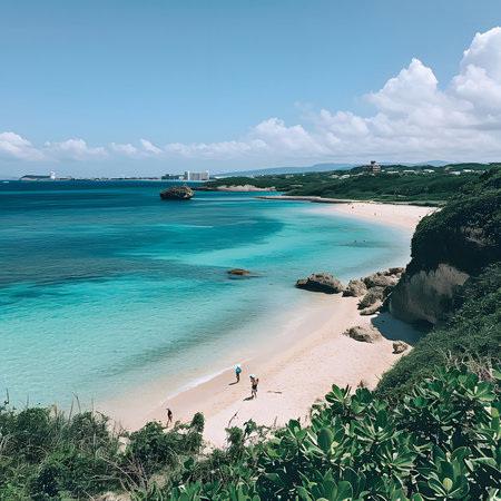 A stunning view of a pristine tropical beach with crystal clear turquoise waters. The beach stretches out towards a horizon of blue sky and fluffy white cloudsの写真素材