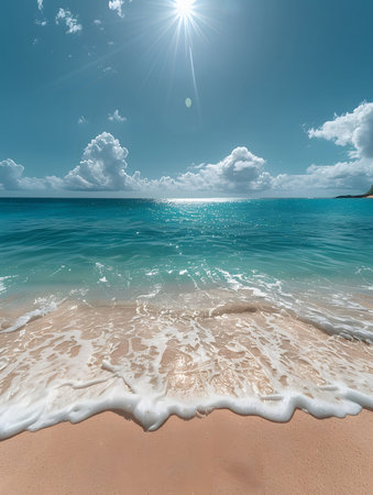 A serene view of a tranquil beach with crystal-clear water, golden sand, and gentle waves lapping at the shore. The sky is bright blue with fluffy clouds and the sun shines brightly.の写真素材