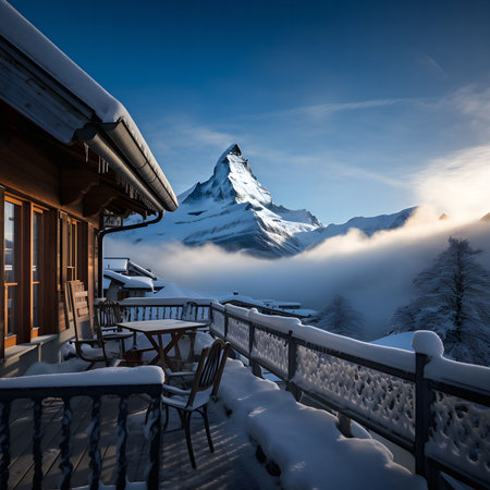 A breathtaking view of a snow-capped mountain peak from a charming Swiss chalet with a balcony and snow-covered landscape.の写真素材