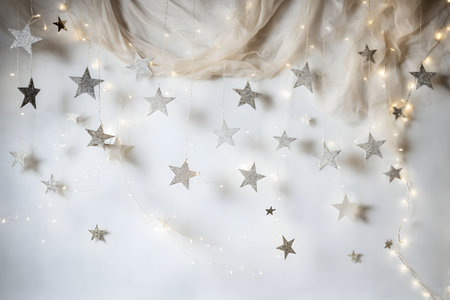 Close-up of a white wall decorated with a string of fairy lights and hanging paper stars for a festive feel.の写真素材