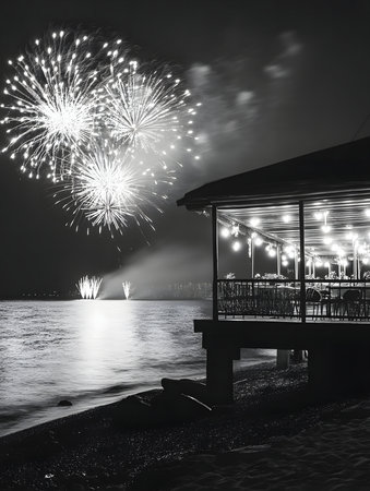 Fireworks explode over a calm body of water, illuminating a lakeside restaurant at night. A beautiful scene.の写真素材