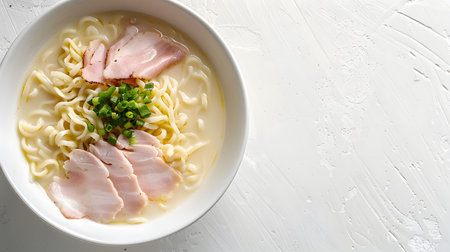 A bowl of creamy noodle soup topped with sliced chicken and pork. Delicious and satisfying.の写真素材