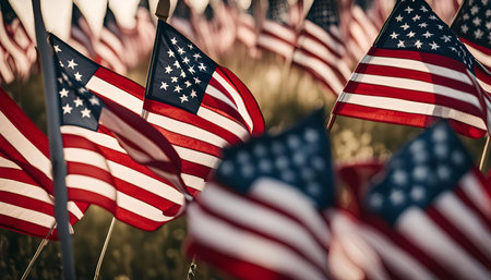 A close-up shot of a field of American flags waving in the wind. The flags are blurred in the background, creating a sense of depth and perspective. The image is a symbol of American patriotism and pride.の写真素材