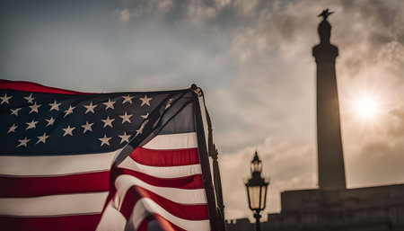 A close-up shot of an American flag waving in the wind against a backdrop of a monument and sunset.の写真素材