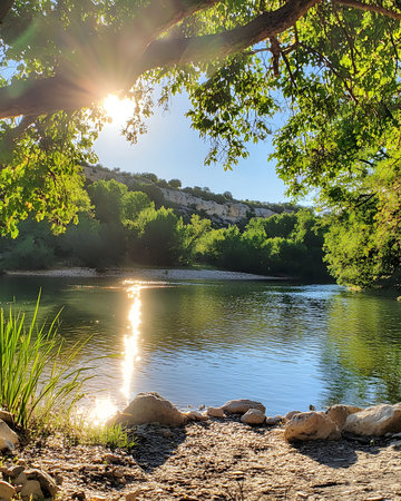 Stunning sunset over a calm river, reflecting the golden light. Lush greenery and serene atmosphere.の写真素材
