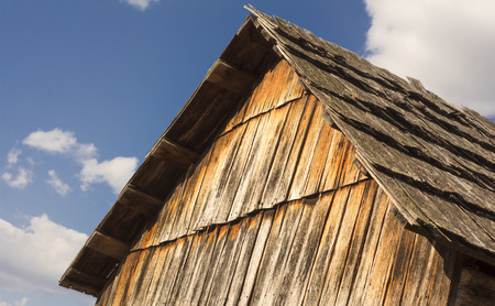 Old barn roof against a blue sky with fluffy cloudsの写真素材