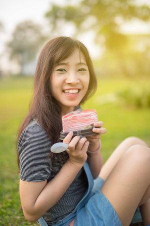 Woman eating A Piece Of cake in Parkの写真素材