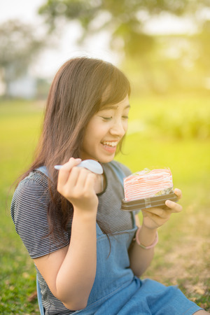 Woman eating A Piece Of cake in Parkの写真素材
