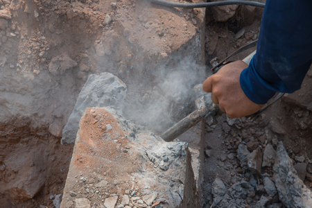 Worker drilling cement concrete floor with machine at construction siteの写真素材