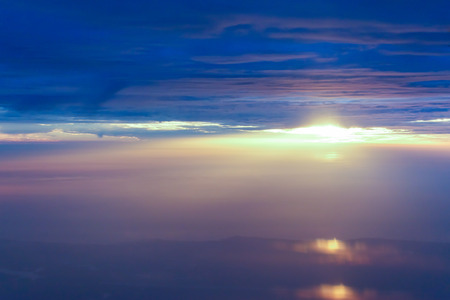 White clouds and blue sky with yellow warm sunrise from airplane window.の写真素材