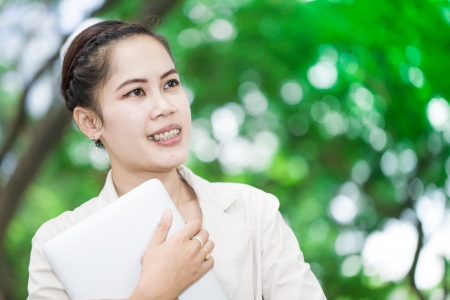 Young beautiful smiling woman hug laptop look to skyの写真素材