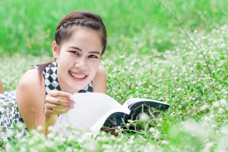 Girl-student lies on lawn and reads textbook の写真素材