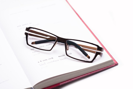 Close up eyeglasses on a document isolated on whiteの写真素材