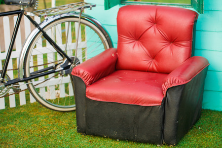 Red sofa with vintage bicycle and green grass in outdoor roomの写真素材