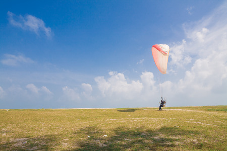 Flying paramotor under blue sky, beach