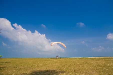 Flying paramotor under blue sky, beach