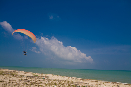 Flying paramotor under blue sky, beachの写真素材