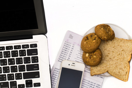 Close up of White work desk with a laptop computer, book bank, bread cup of coffeeの写真素材