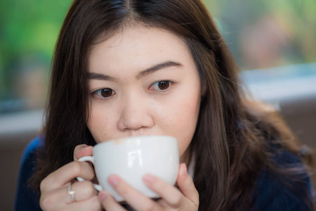 Asian woman Sitting In Cafe Bar and drinking coffeeの写真素材
