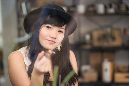 Young asian woman drinking coffee through the mirror in a trendy vintage cafeの写真素材