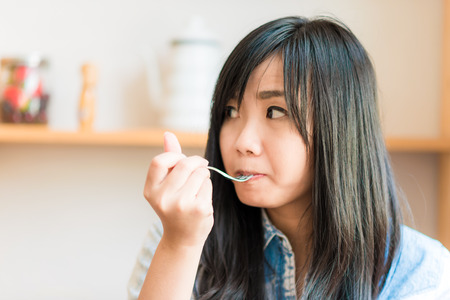 Smiling asian woman eating some strawberry cake in bakery cafe, woman hold cakeの写真素材